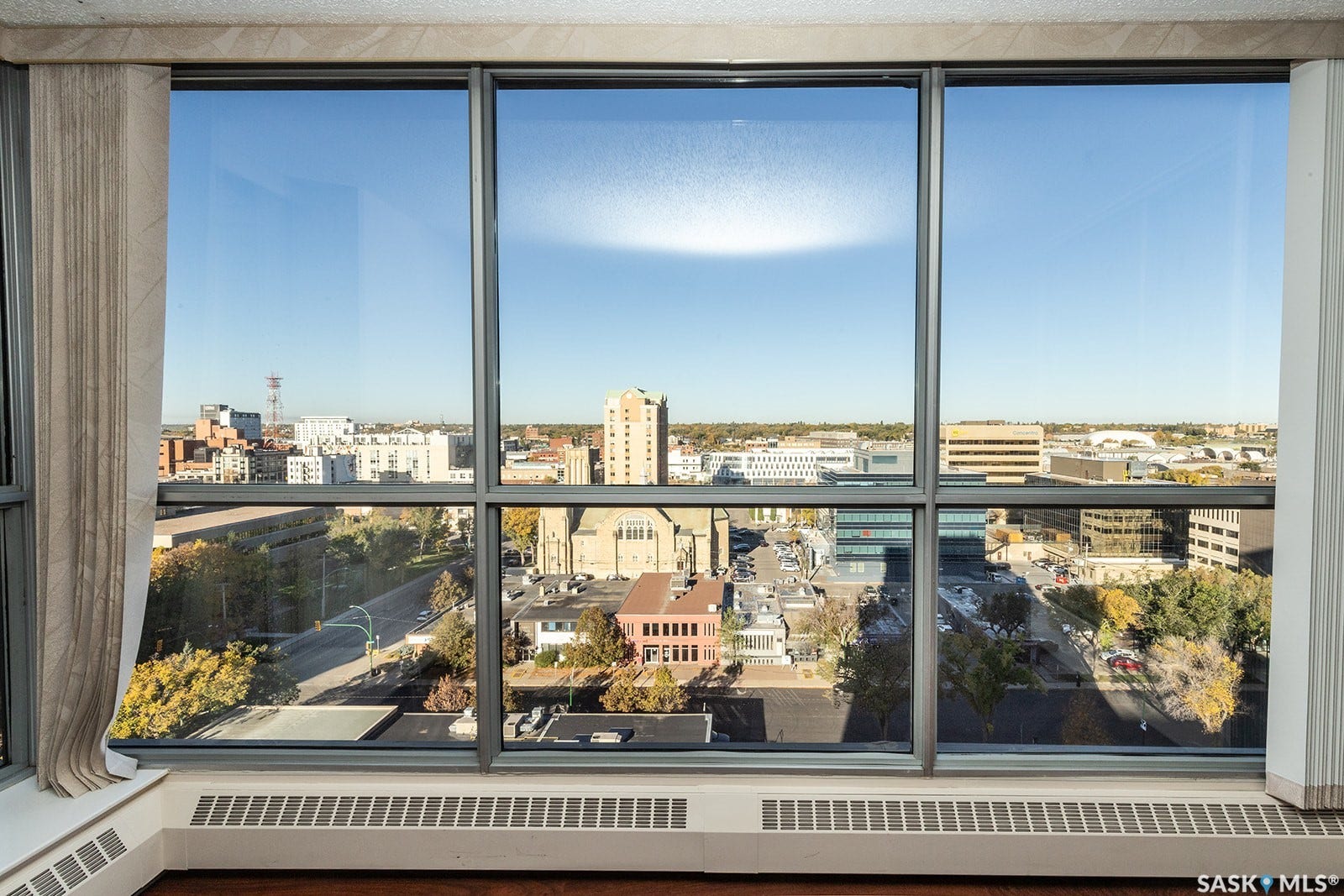 Large windows with city view, and dark laminate flooring