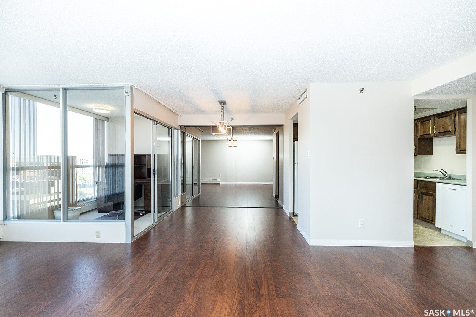 Laminate flooring, full-height windows with vertical blinds, large mirrored wall, glass-enclosed office space that can be removed if desired