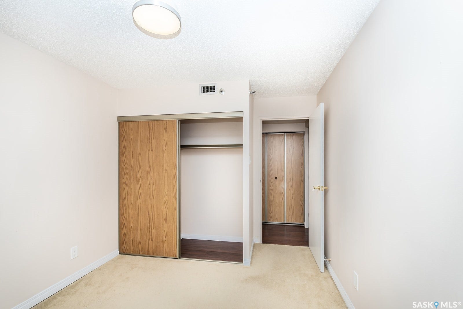 Second bedroom with wall-to-wall carpeting, wood-finish sliding closet doors, and a ceiling-mounted light fixture