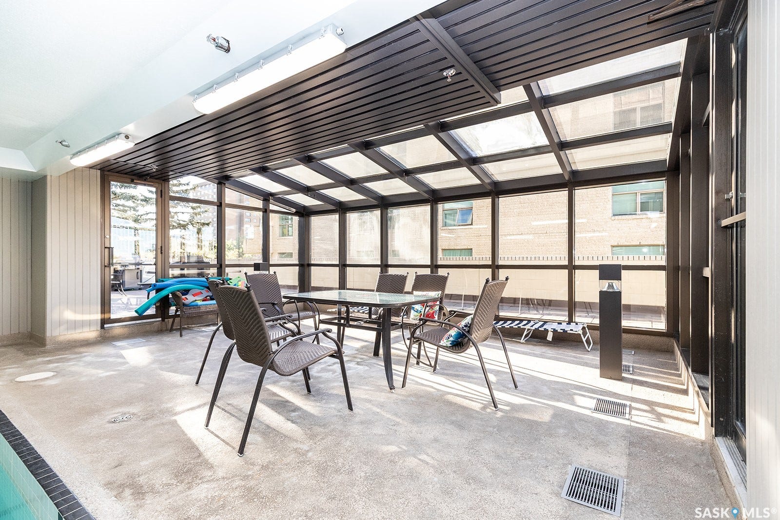 Enclosed patio with a transparent roof, full-height windows, and concrete flooring