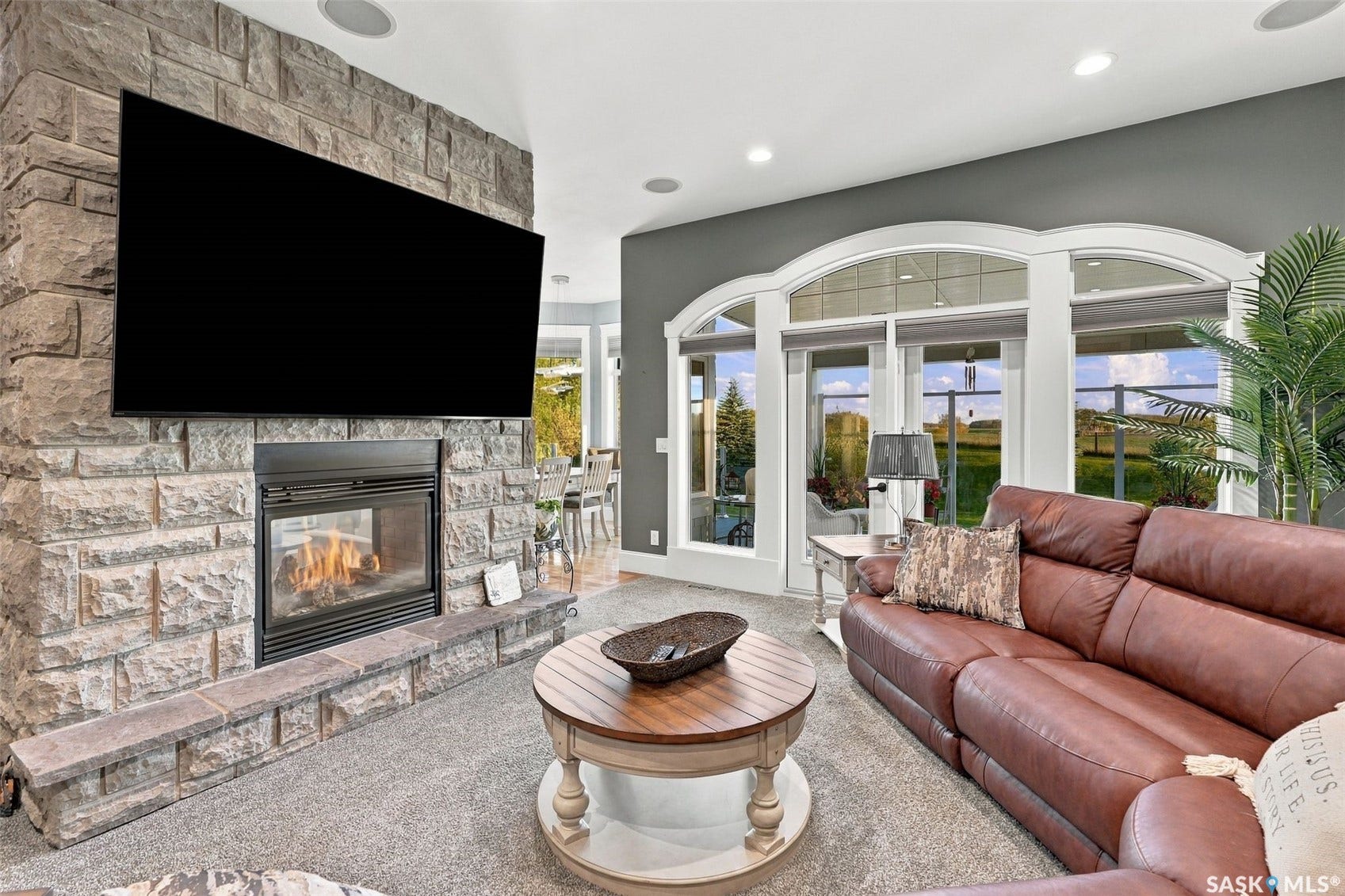 Stone-clad fireplace with hearth, arched windows, and integrated recessed lighting