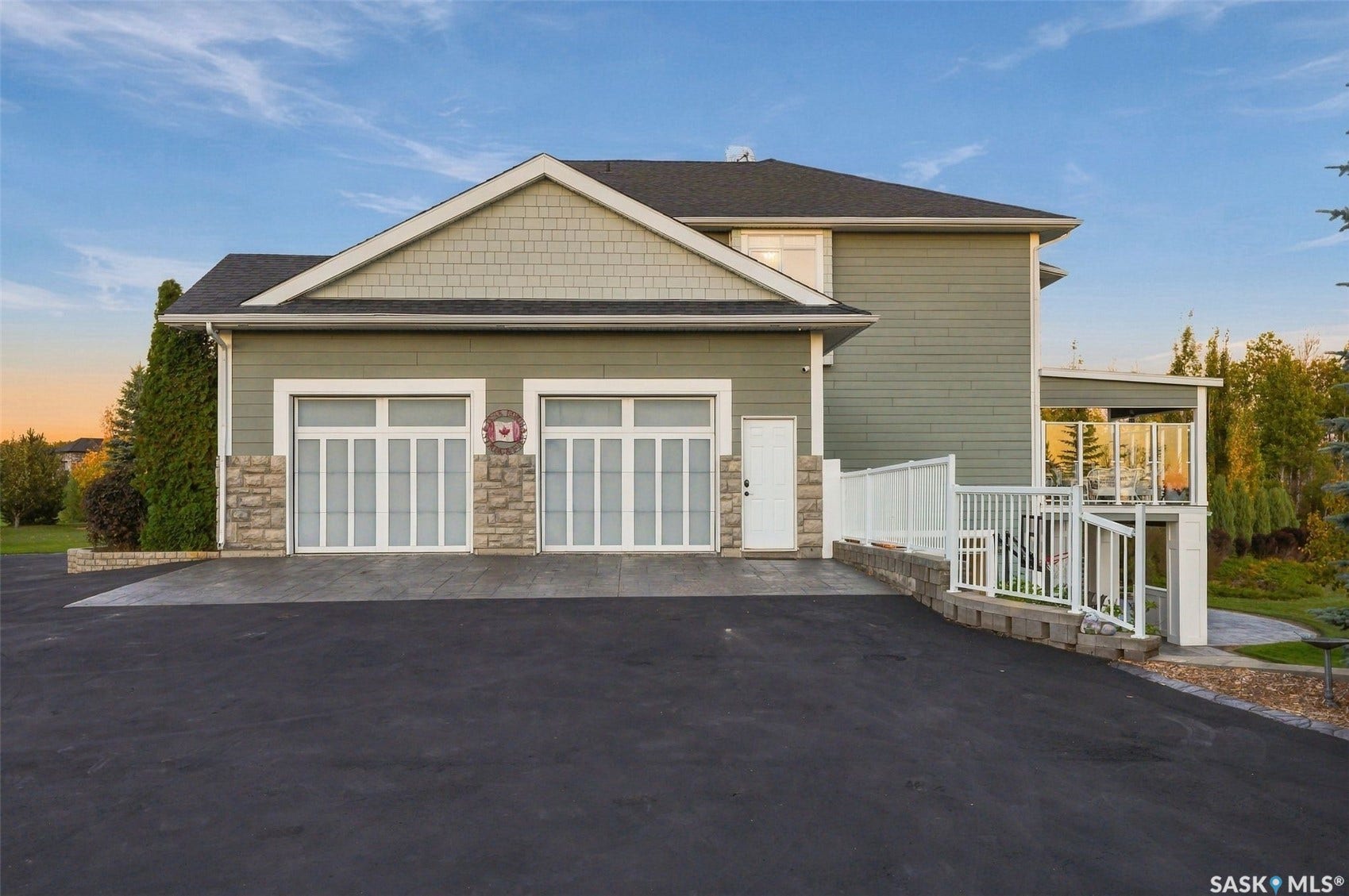 Exterior featuring two garage doors with window panels, stone accents, and siding