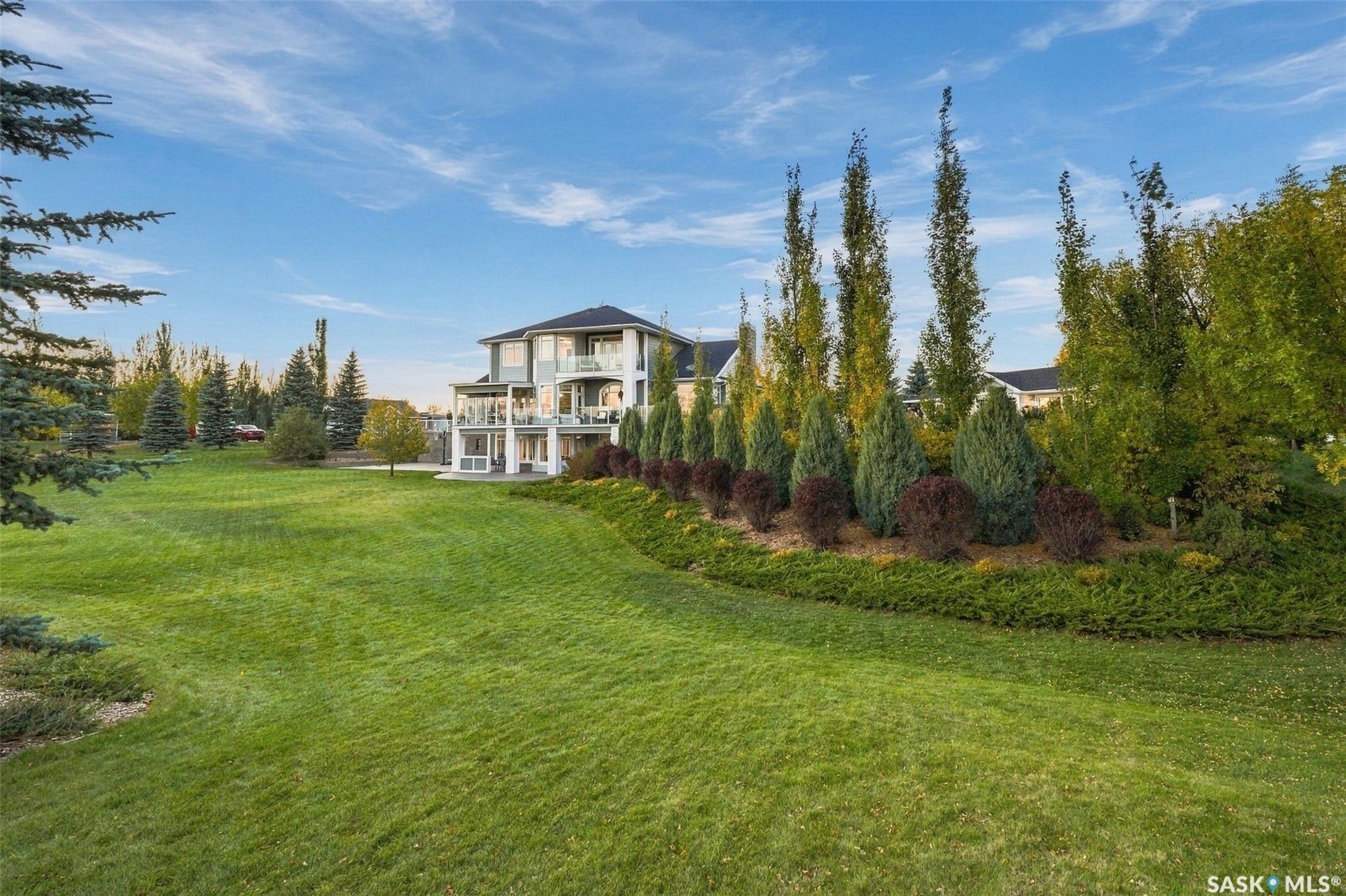 Expansive green lawn with a multi-level house featuring multiple balconies