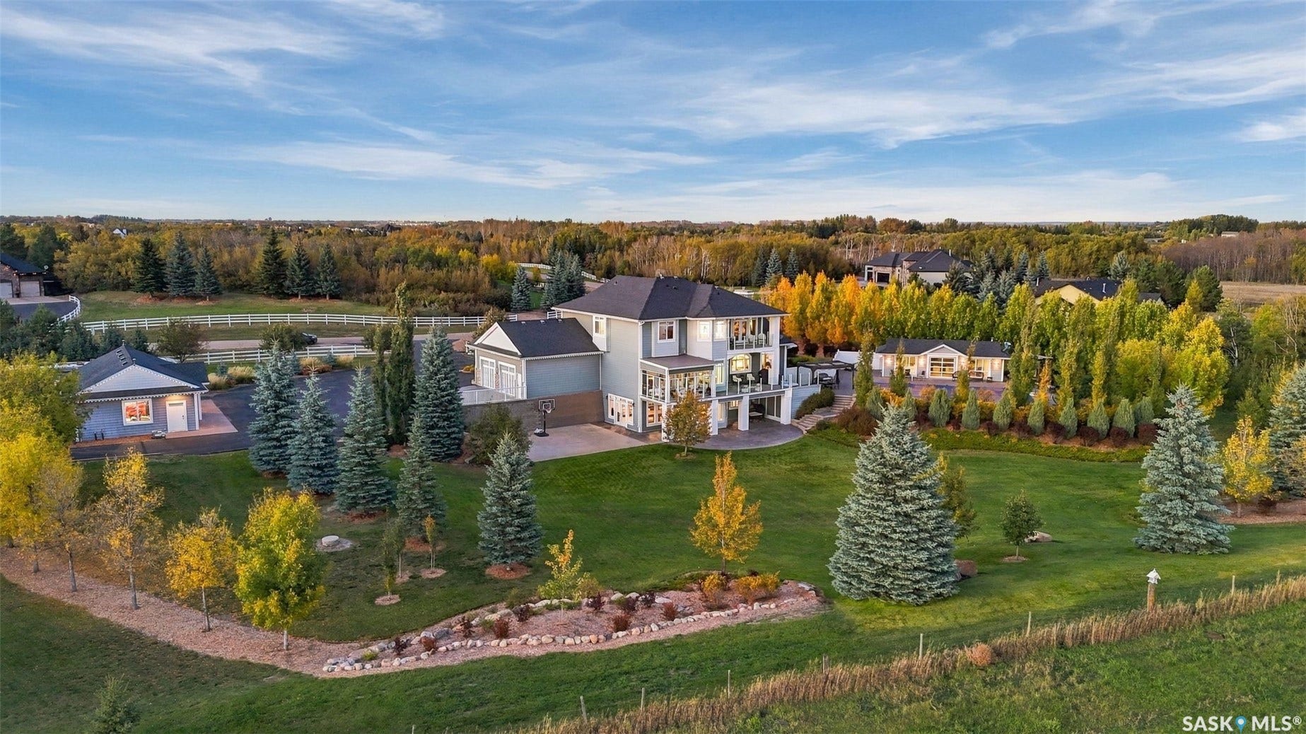 Expansive property featuring a multi-level residence, detached garage, and a large landscaped lawn with mature trees