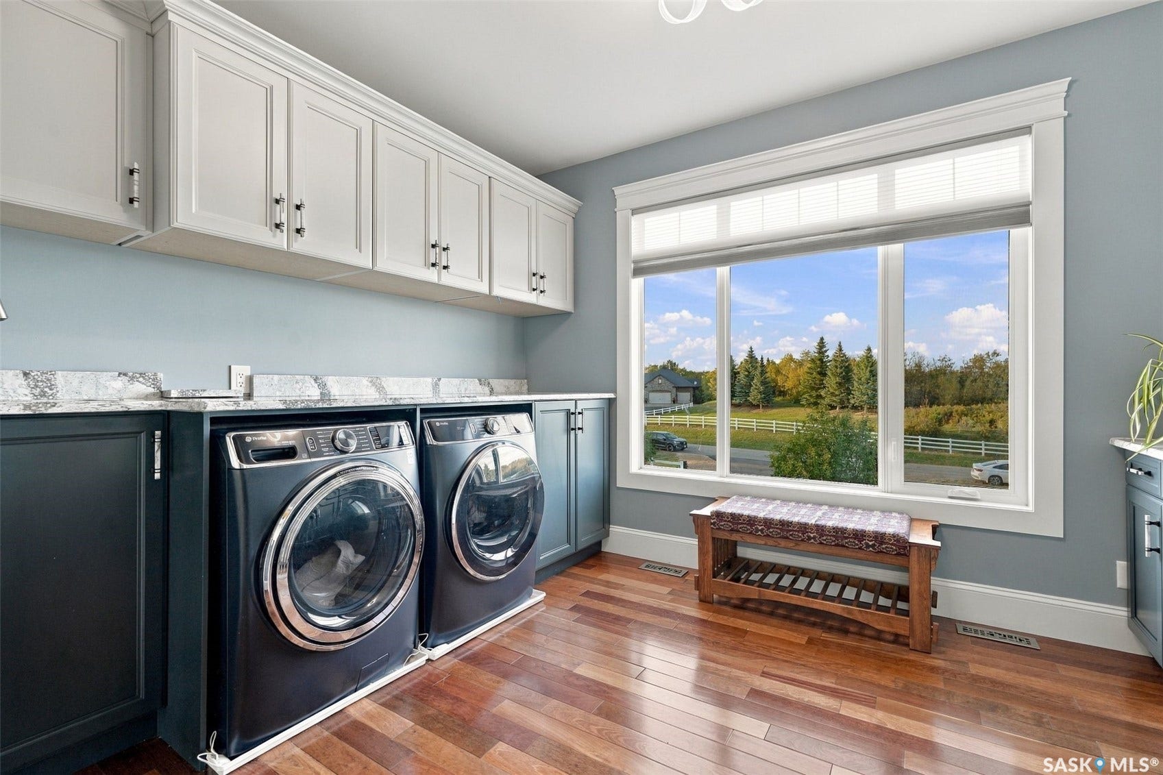 Hardwood flooring, light-toned upper cabinetry, dark lower cabinetry, light-toned countertop, and a large window