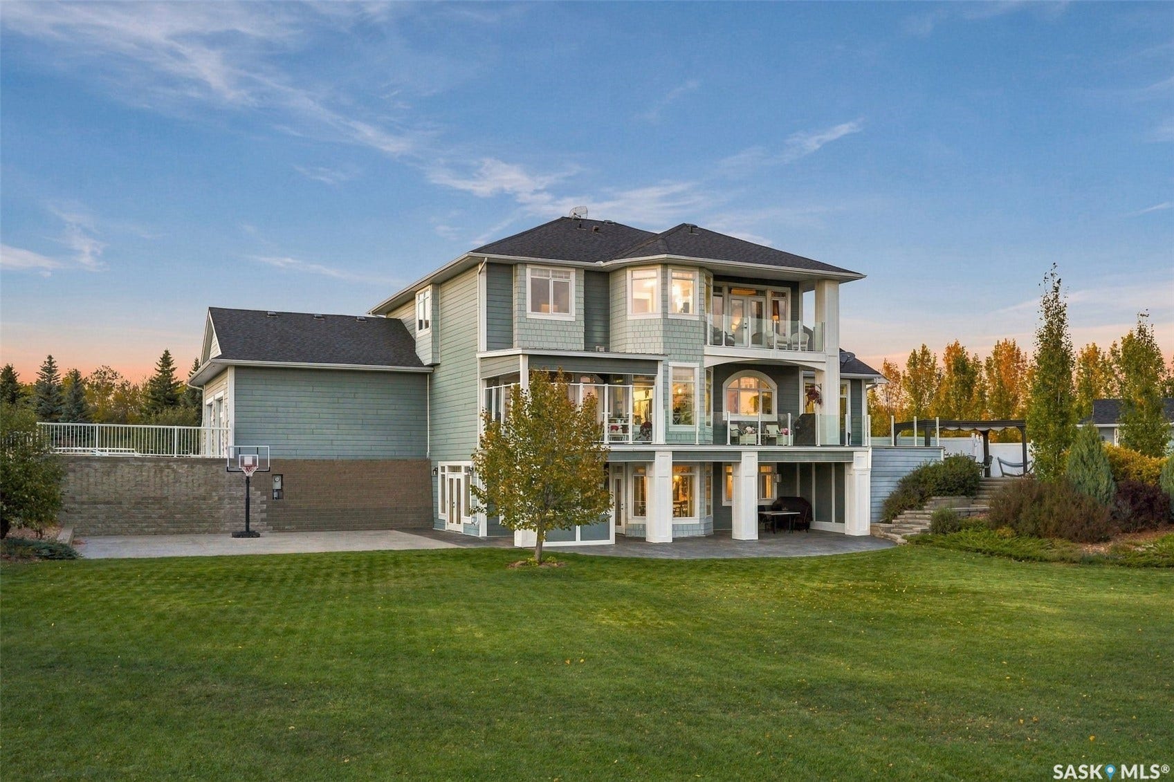 Multi-story residence with extensive exterior glazing, multiple balconies, and a patio area
