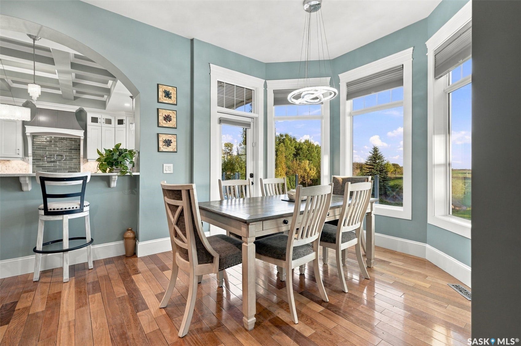 Wood-finish flooring with a modern chandelier and bay windows