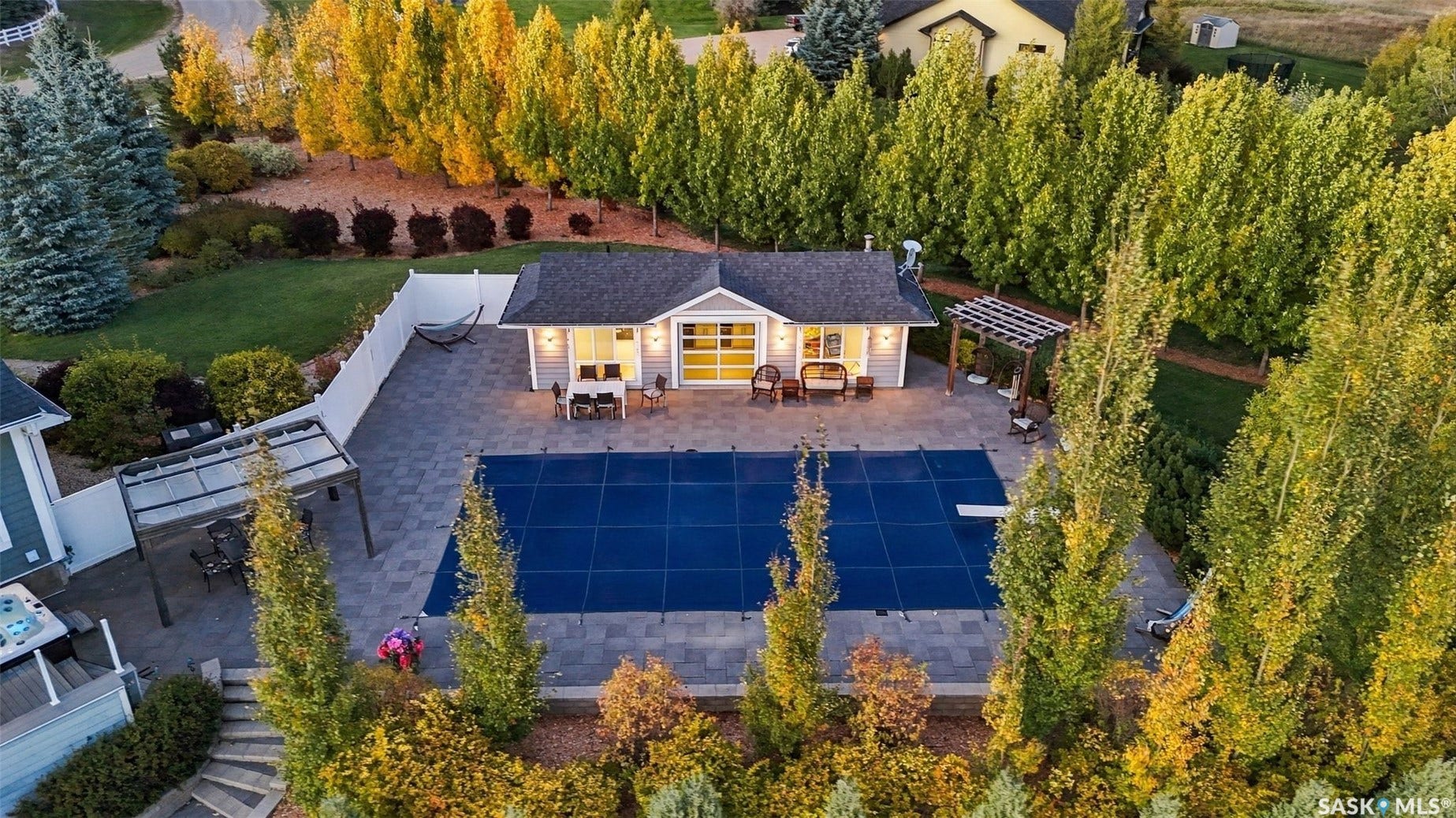 Expansive pool area with paver surround, diving board, and adjacent pergola