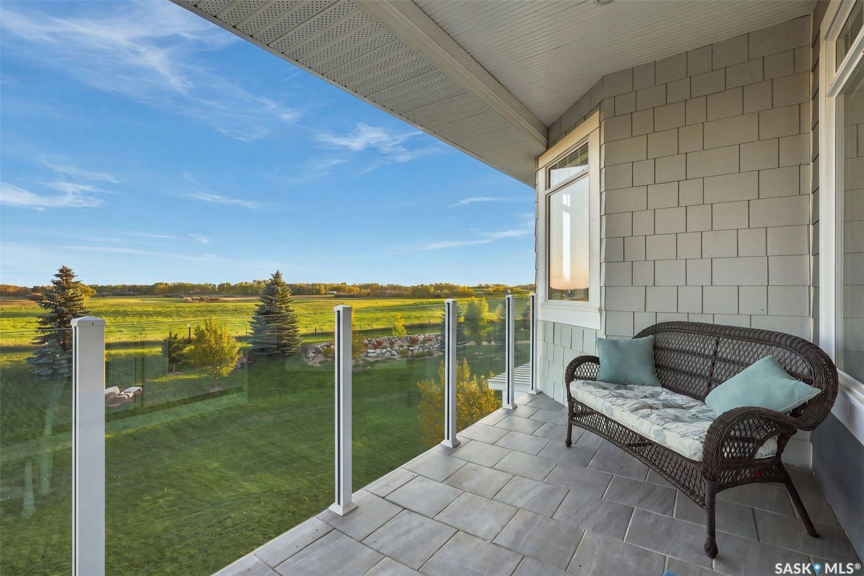 overed balcony off primary bedroom with paver flooring, glass railing, and a window featuring horizontal siding