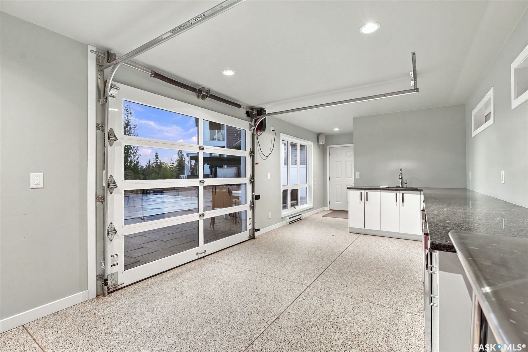 Pool house with full glass panel garage door, polished concrete flooring, built-in cabinetry, integrated sink, and recessed lighting