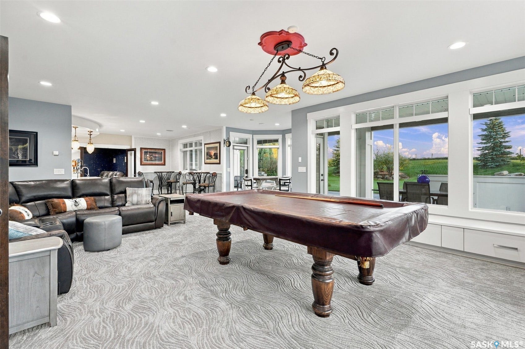 Spacious recreational area featuring patterned carpeting, recessed lighting, and a decorative chandelier