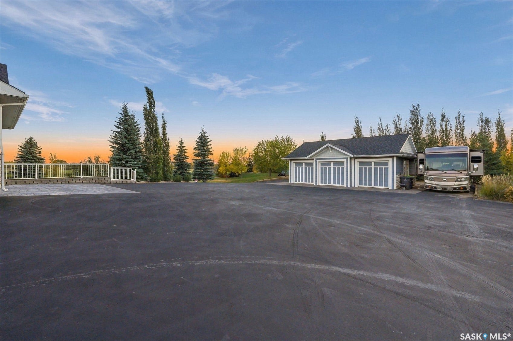 Expansive paved parking area, multi-bay garage with paneled doors, and a stone-accented exterior