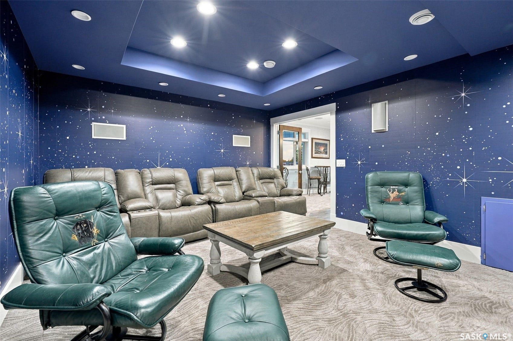 Recessed lighting throughout, accent lighting in ceiling tray, dark blue walls with star detailing, and light-toned patterned carpeting