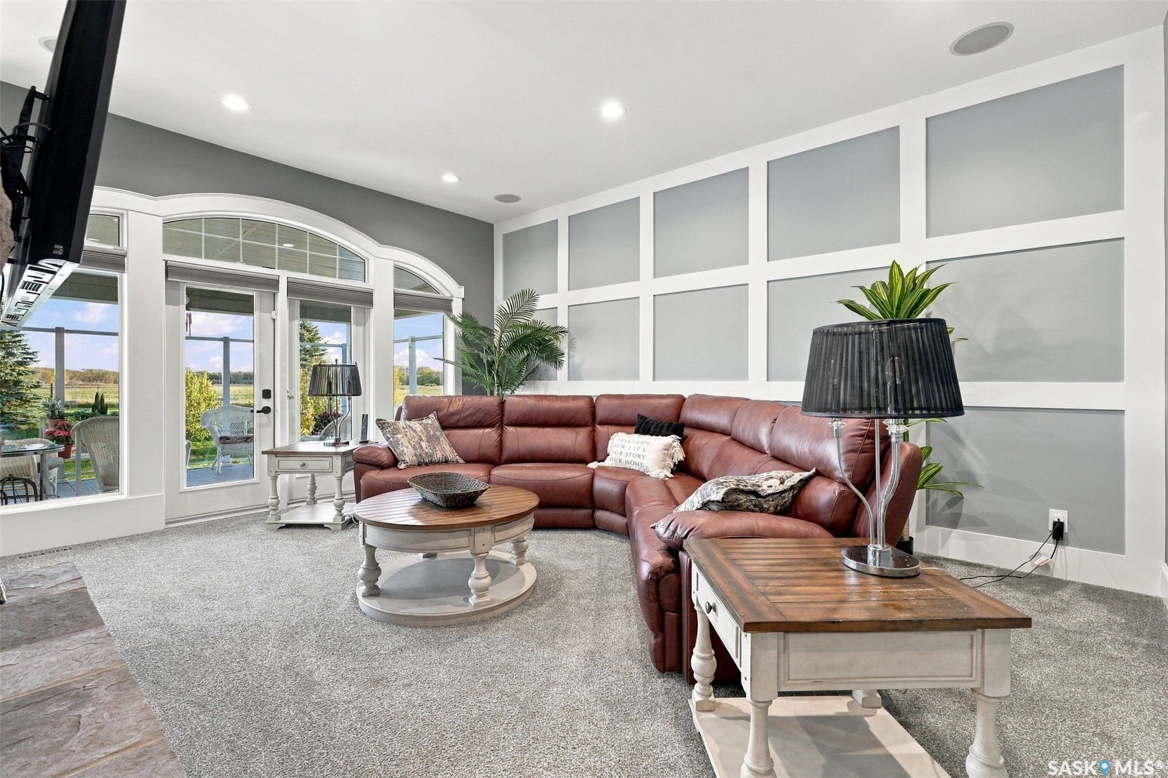 Expansive room with neutral carpeting, recessed lighting, decorative wall paneling, and a floor-to-ceiling arched glass door