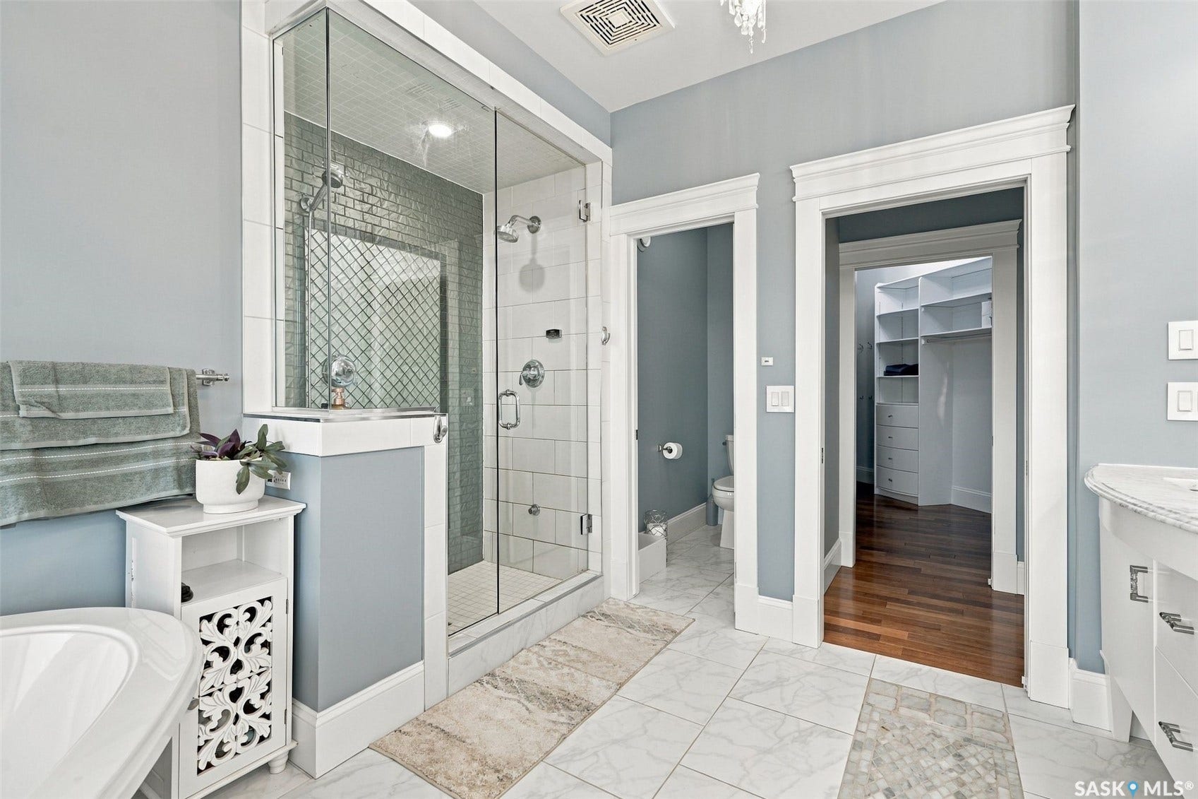 Glass-enclosed steam shower with tile surround, dual shower heads, and an integrated bench