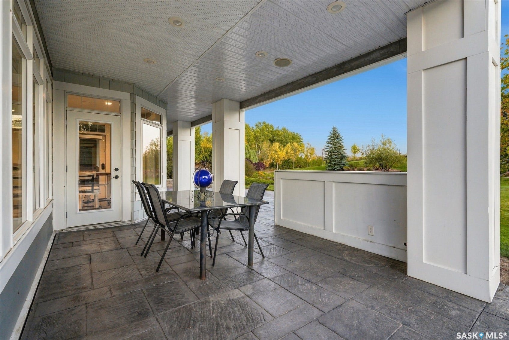 Covered patio featuring stamped concrete flooring, white paneled columns, a beadboard ceiling, and multiple exterior windows