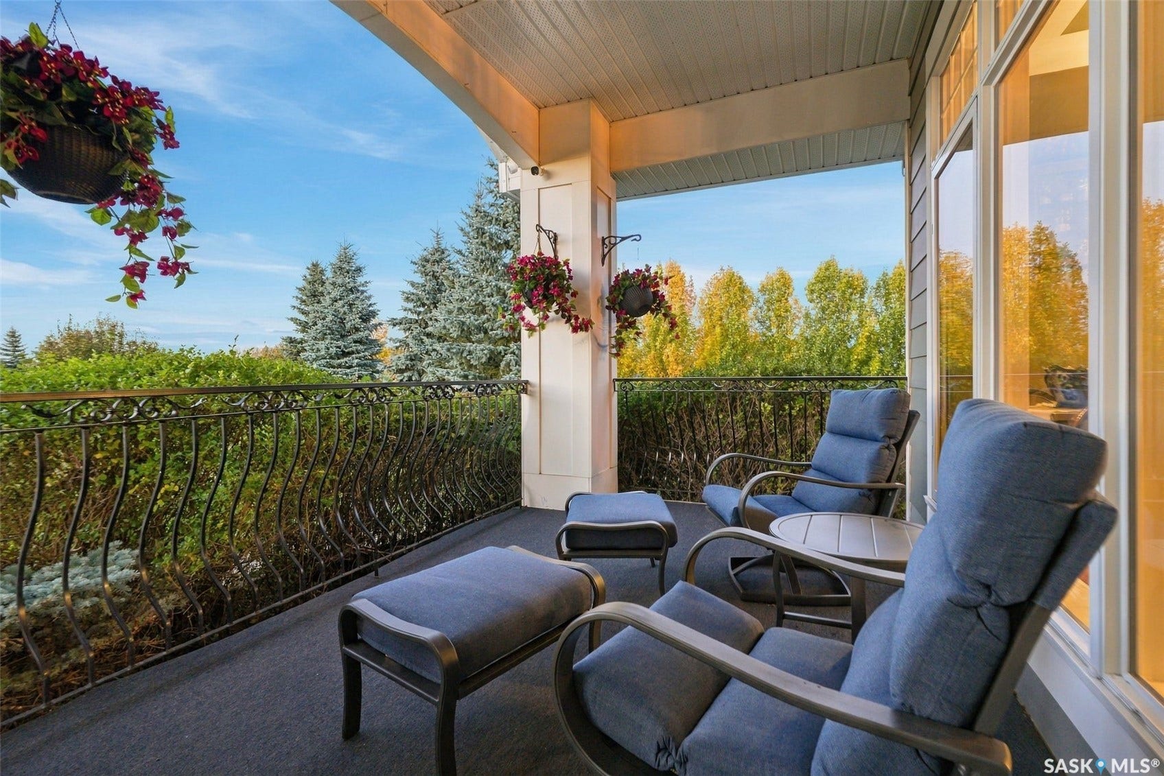 Covered front porch featuring a decorative wrought iron railing, full-height windows, and a textile-covered surface