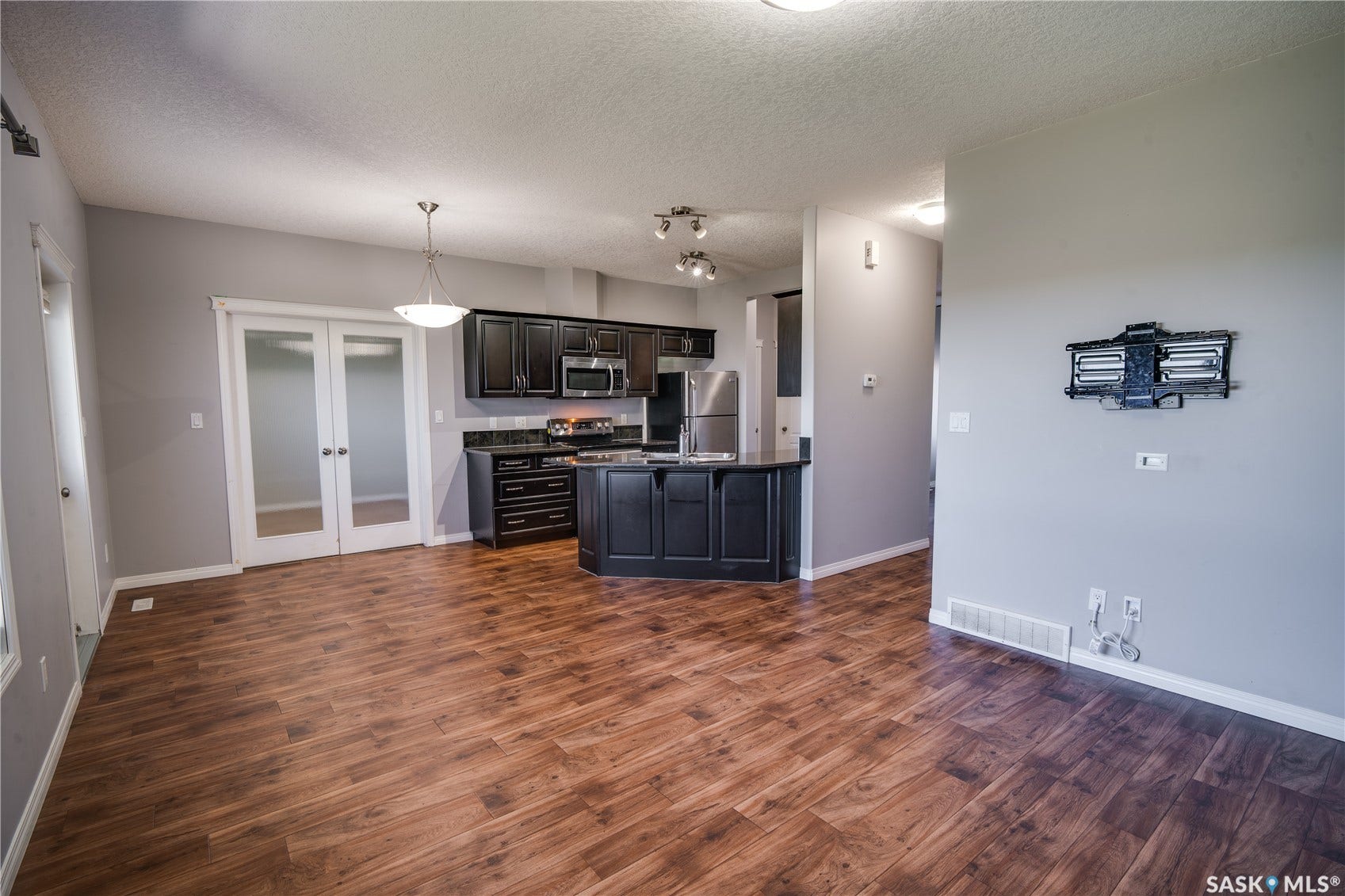 Wood-finish flooring throughout, dark wood cabinetry, and stainless steel appliances