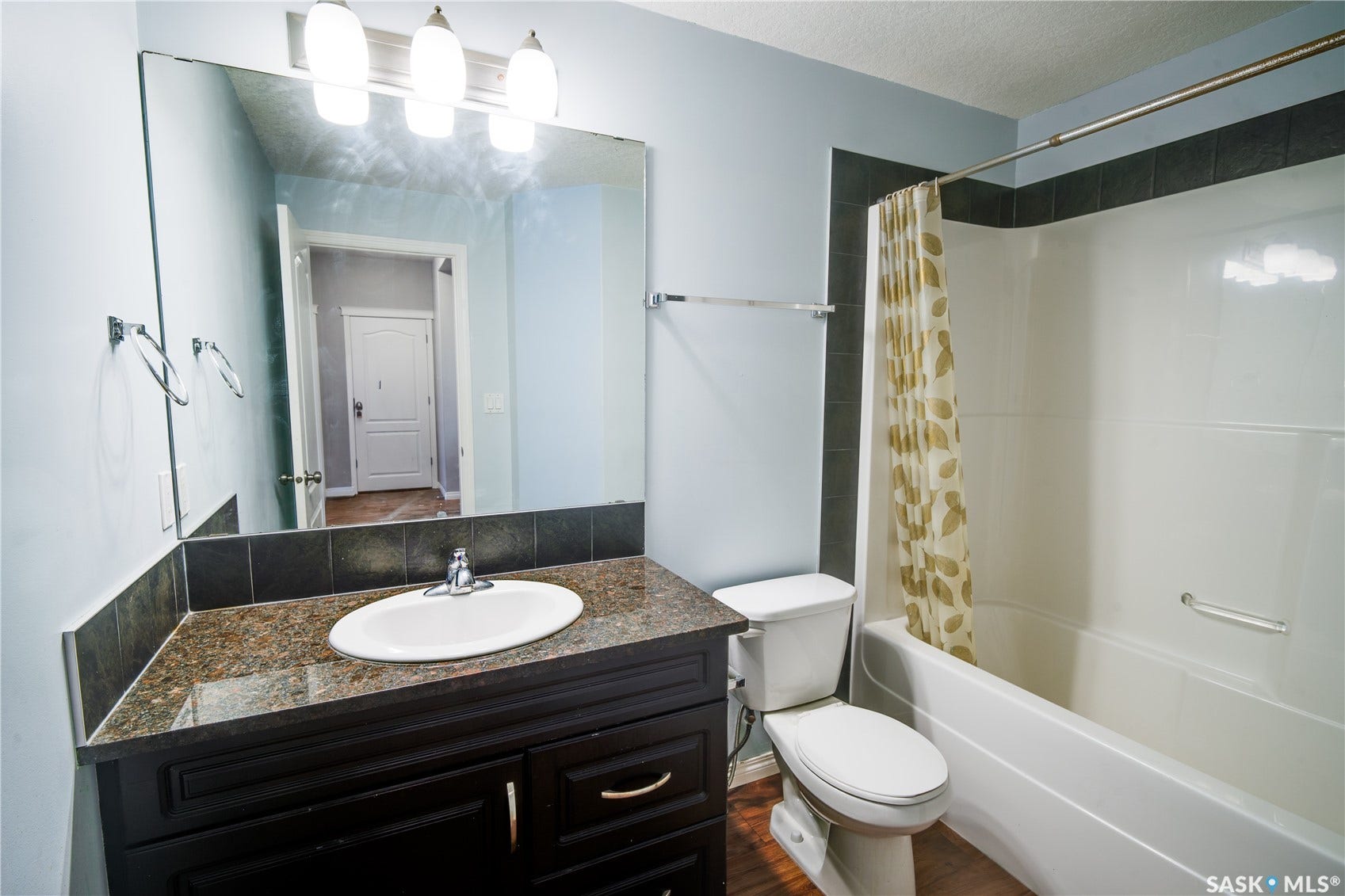 Vanity with a granite-style countertop, undermount sink, and dark wood-finish cabinetry