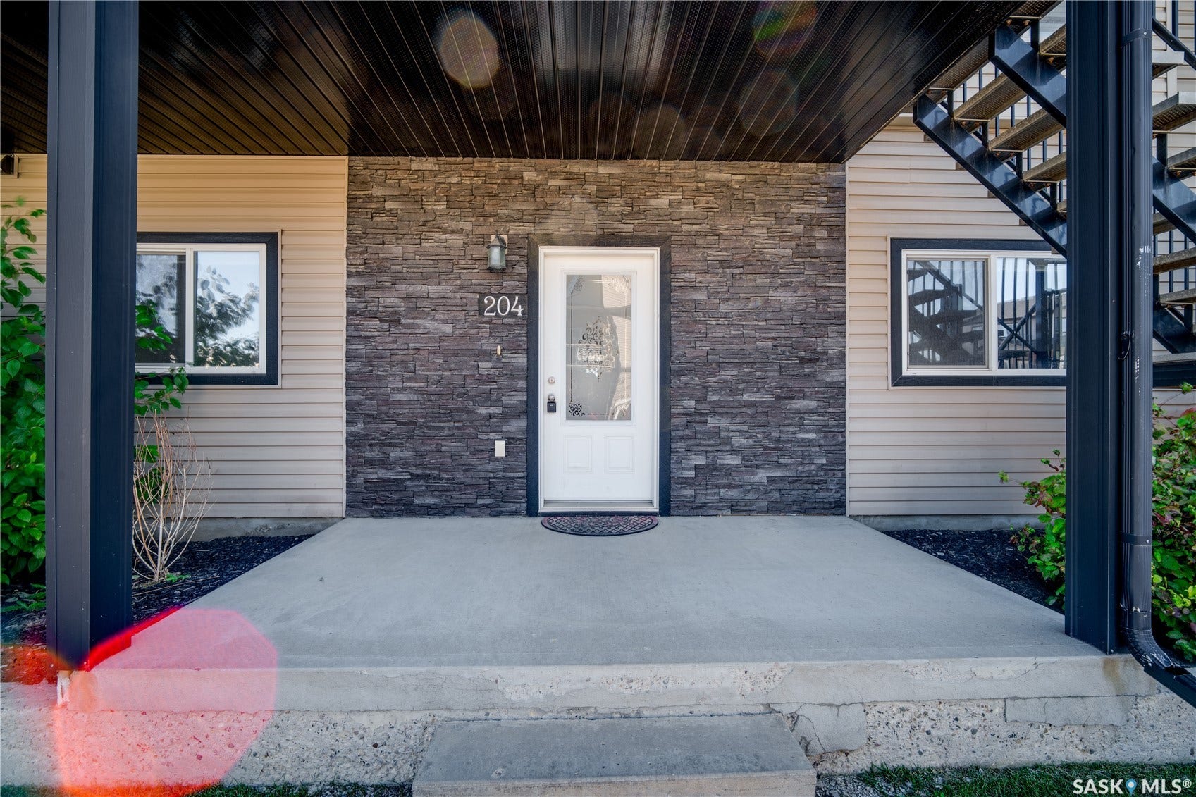 Entryway featuring a white door with decorative glass, stone veneer accent wall, and horizontal siding