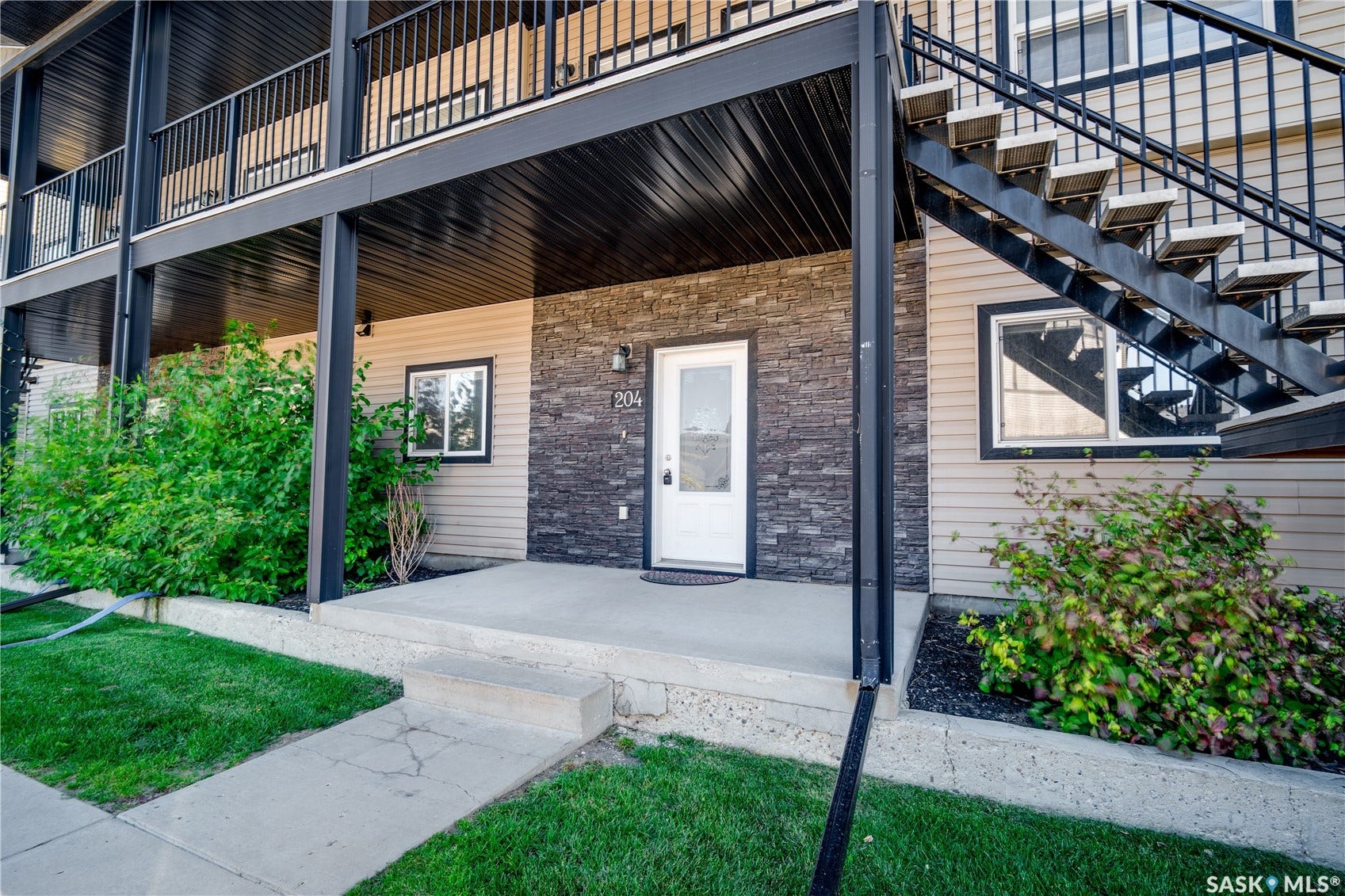 Exterior featuring stacked stone accents, horizontal siding, concrete porch, and a white entry door