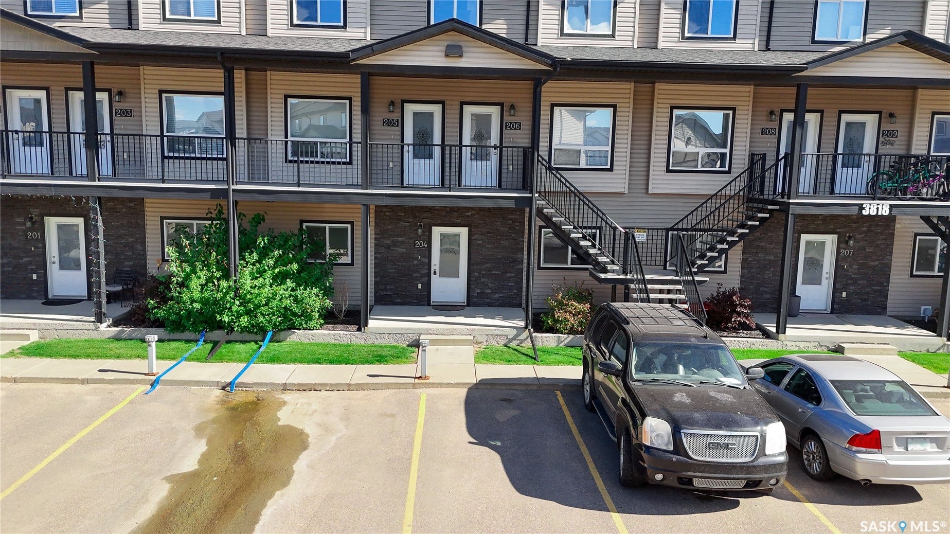 Multi-level building with individual exterior entrances, private balconies with metal railings, and dual exterior staircases