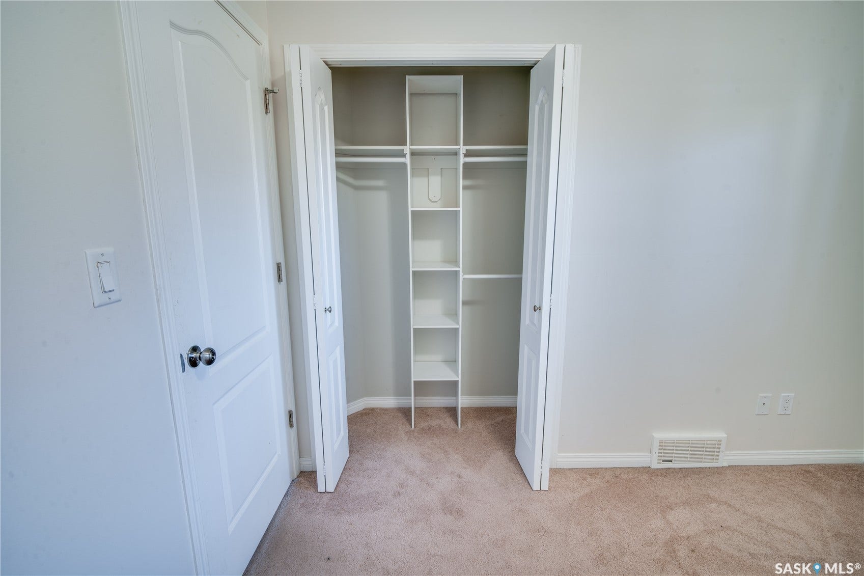 Closet with built-in shelving, hanging rods, and light-colored carpeting