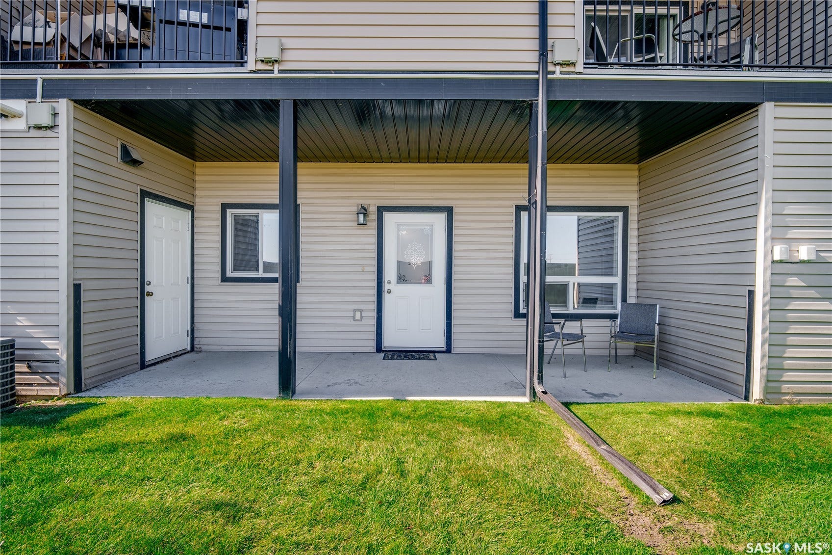 Covered patio with a concrete surface, featuring two exterior doors and a window