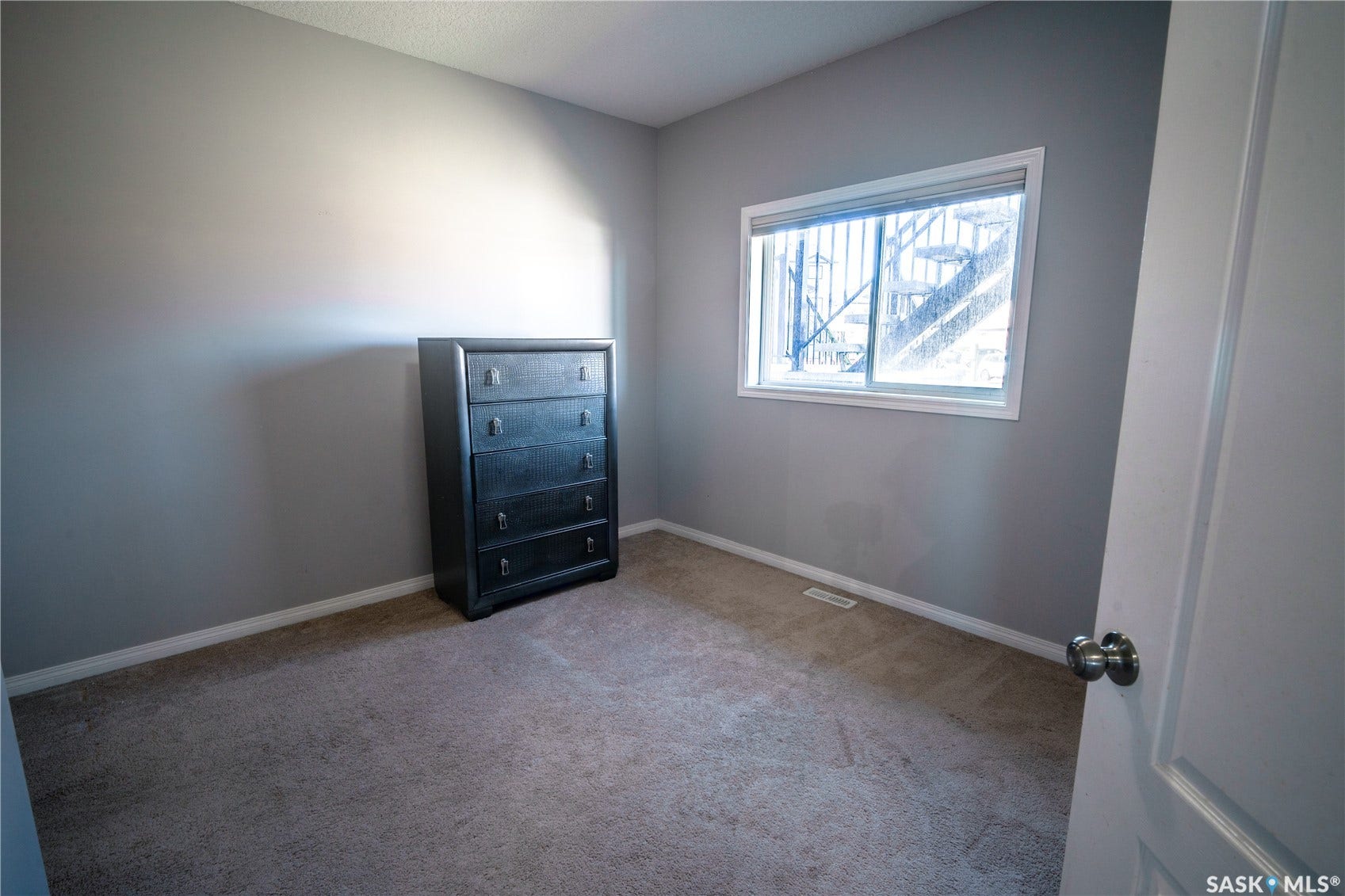 Carpeted room with a double-pane window, white trim, and light gray walls