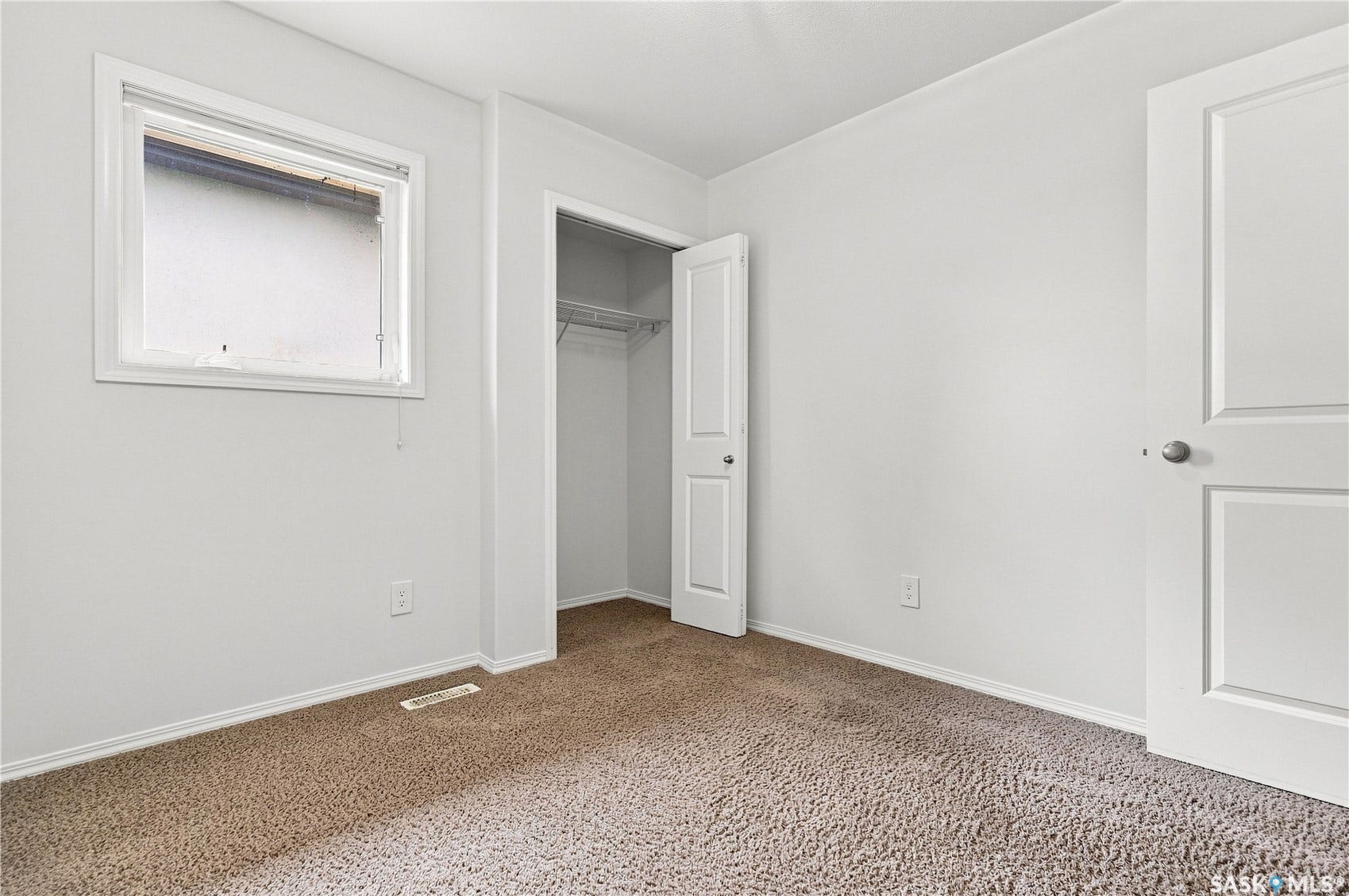 Light-toned carpet flooring, white walls, and a white-framed window
