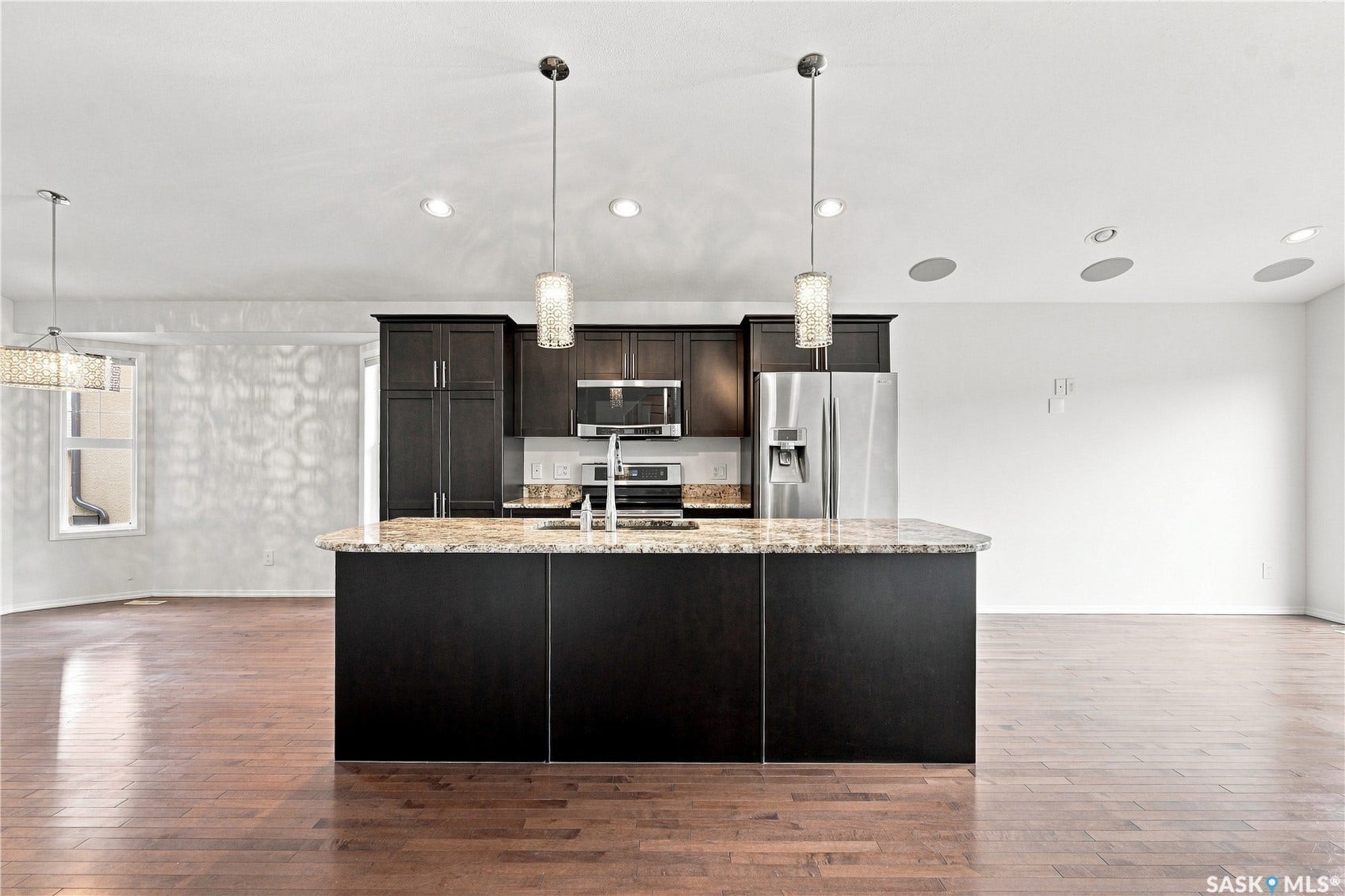 Hardwood-finish flooring throughout, recessed lighting, and a kitchen island with pendant lighting