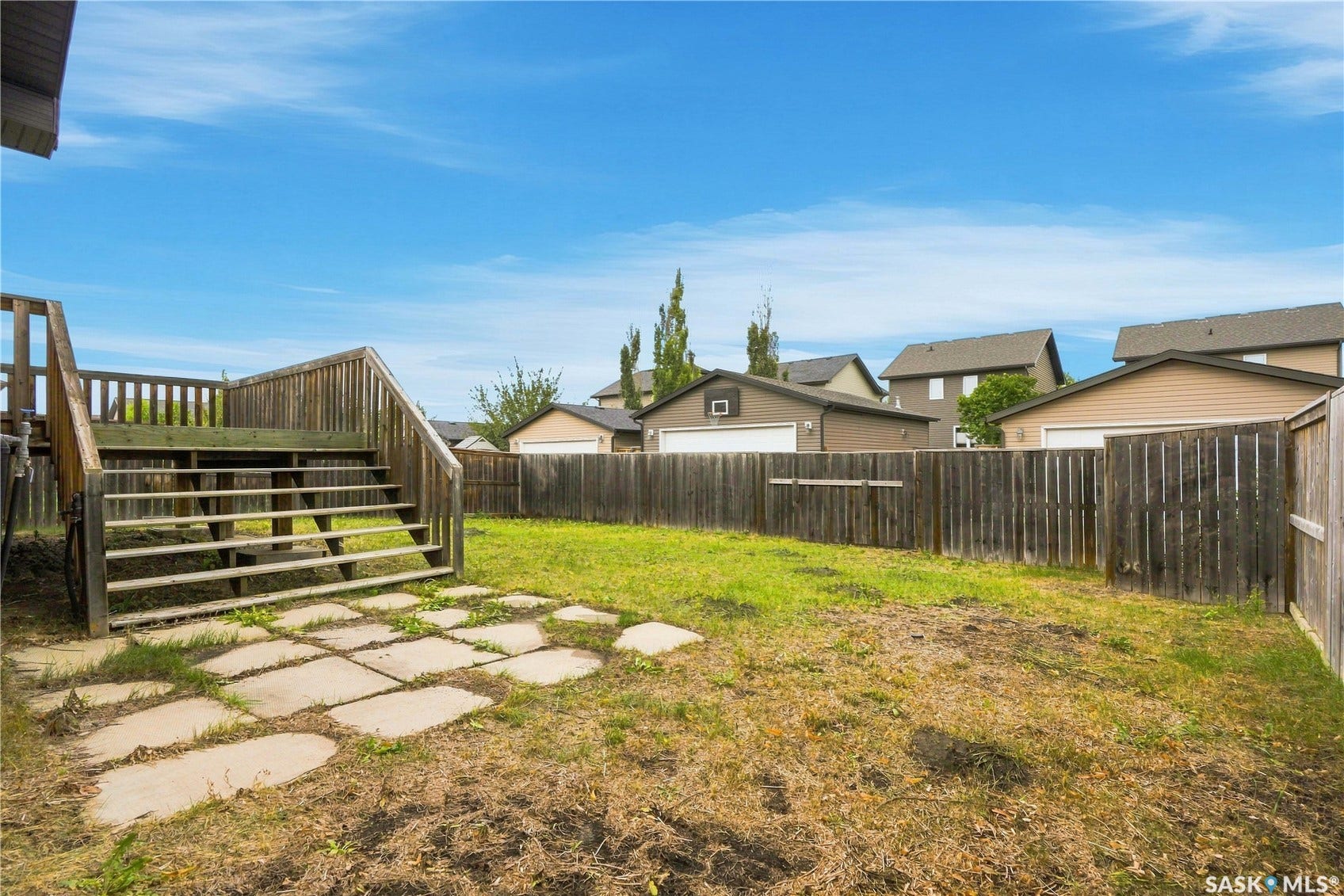 Fenced backyard with wood deck and stone paver patio