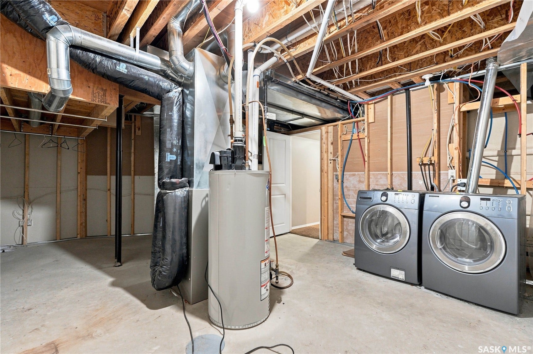 Unfinished basement with exposed wood framing, concrete flooring, and utility installations