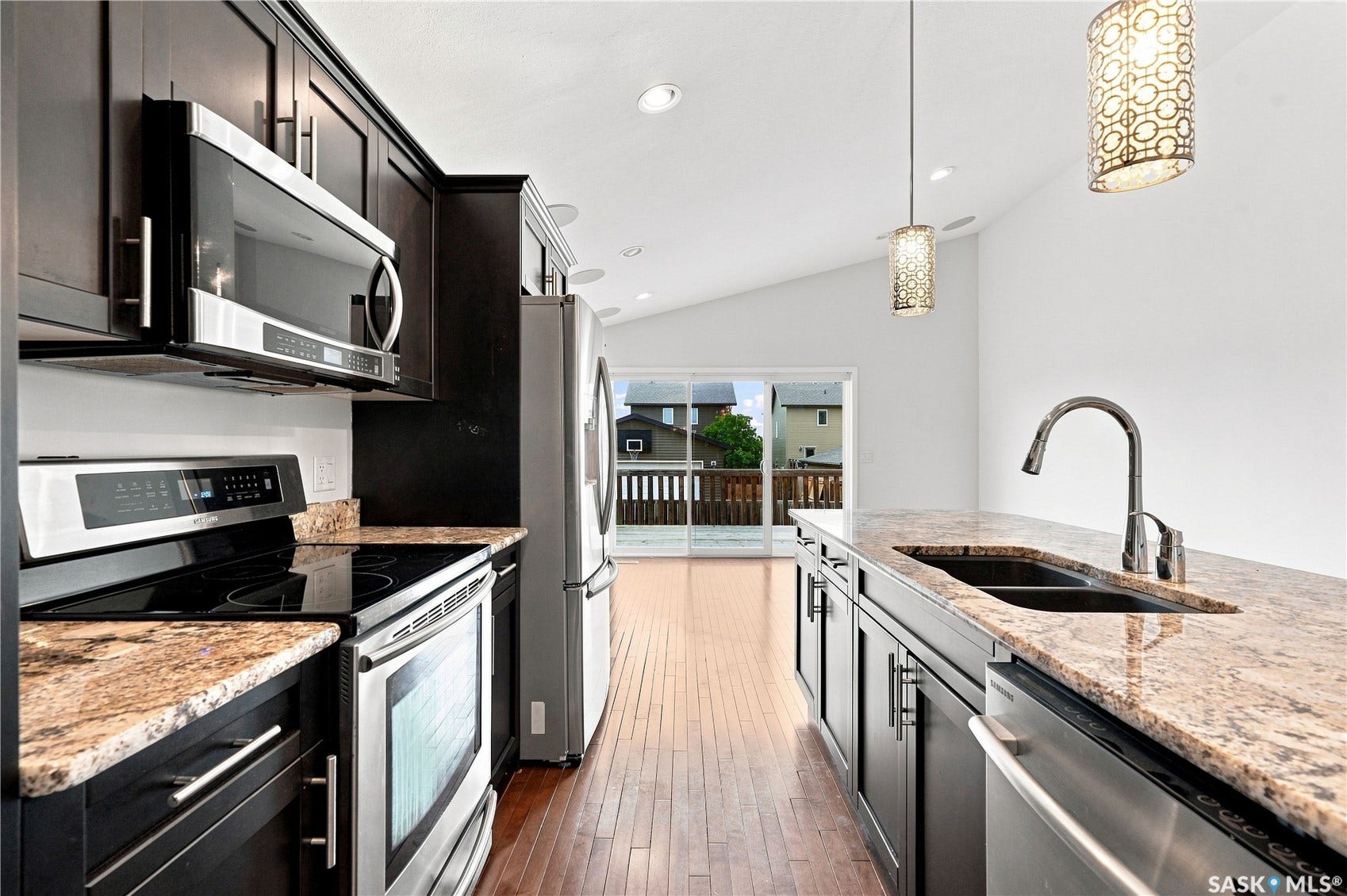 Kitchen featuring dark wood cabinetry, stainless steel appliances, granite countertops, and hardwood flooring