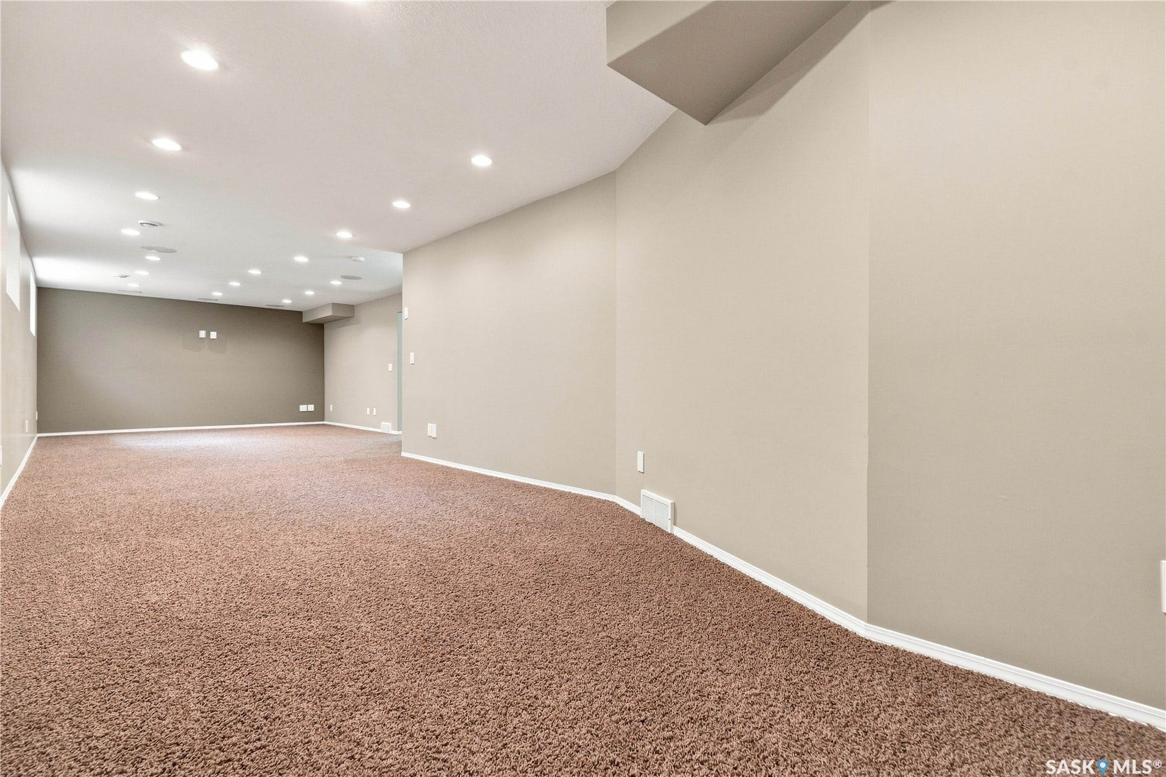 Expansive carpeted area with recessed lighting and neutral wall tones