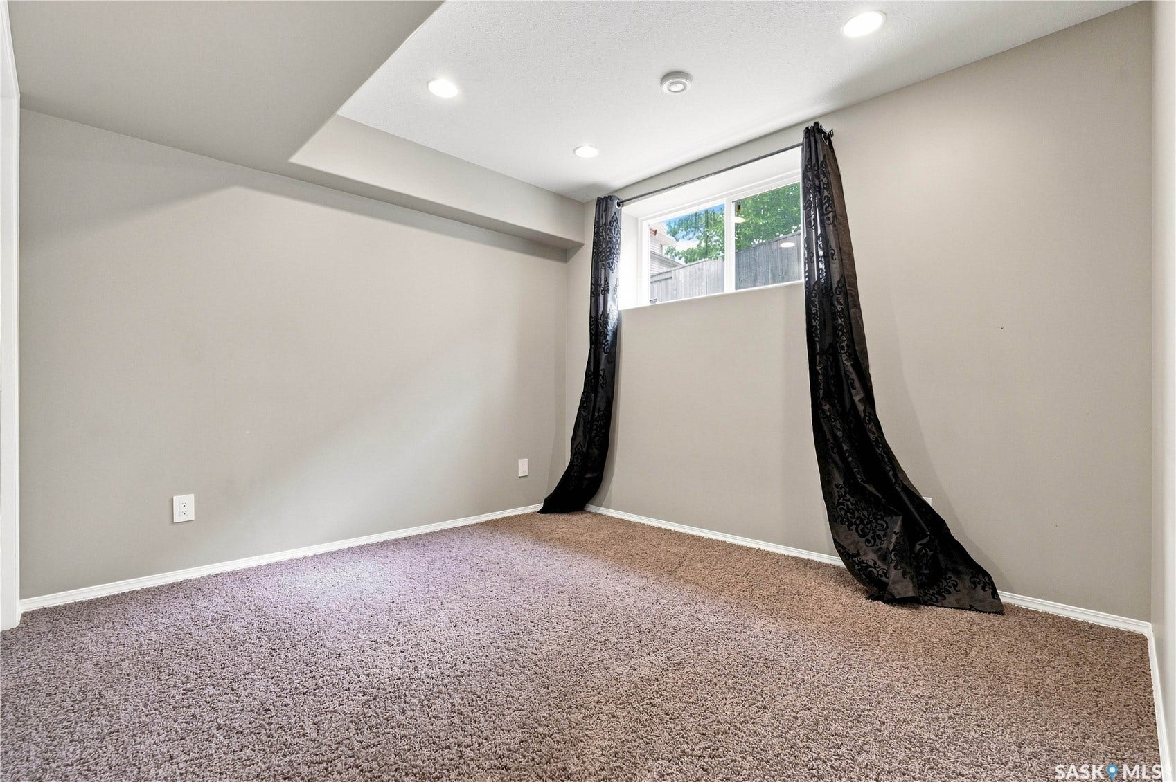 Recessed lighting illuminates the space, featuring a window and plush carpeting