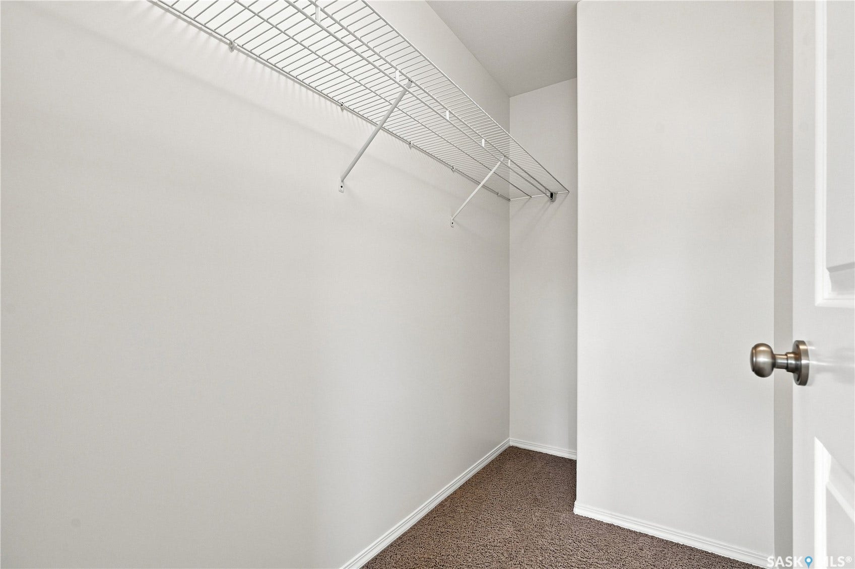 Walk-in closet with wire shelving, neutral wall paint, and dark carpet