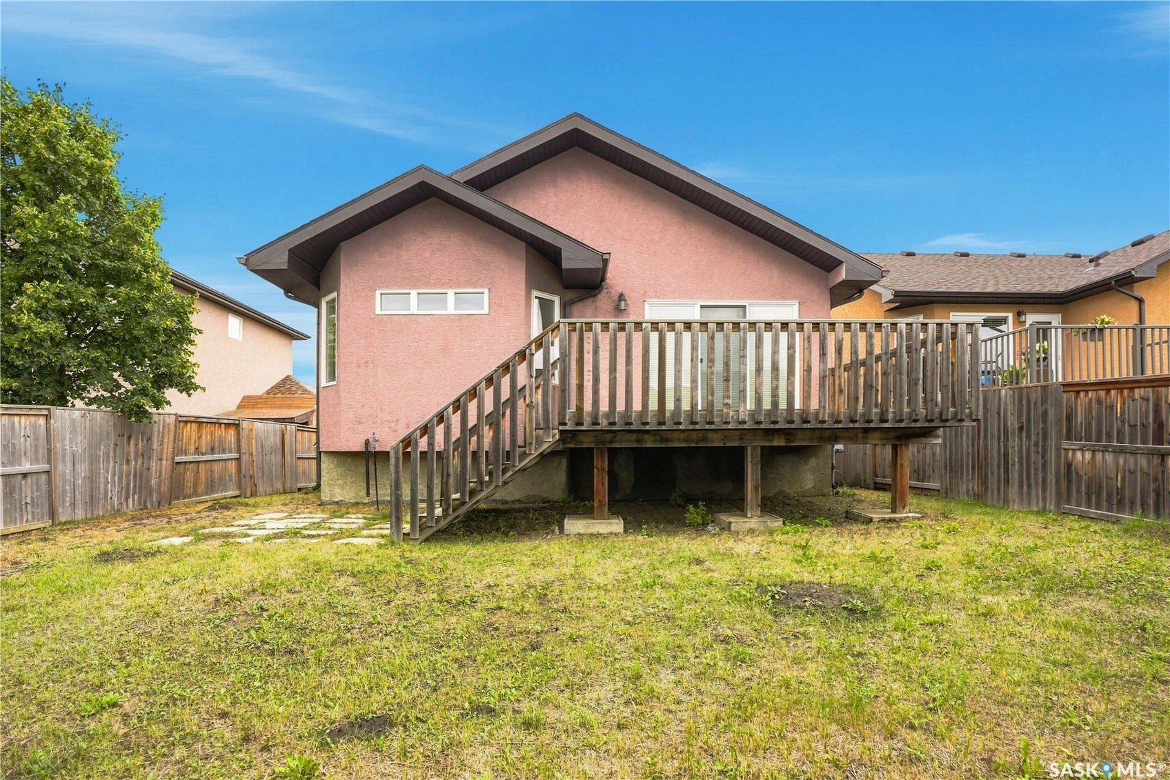 Raised wood deck with privacy railing, exterior stucco siding, and a fenced perimeter