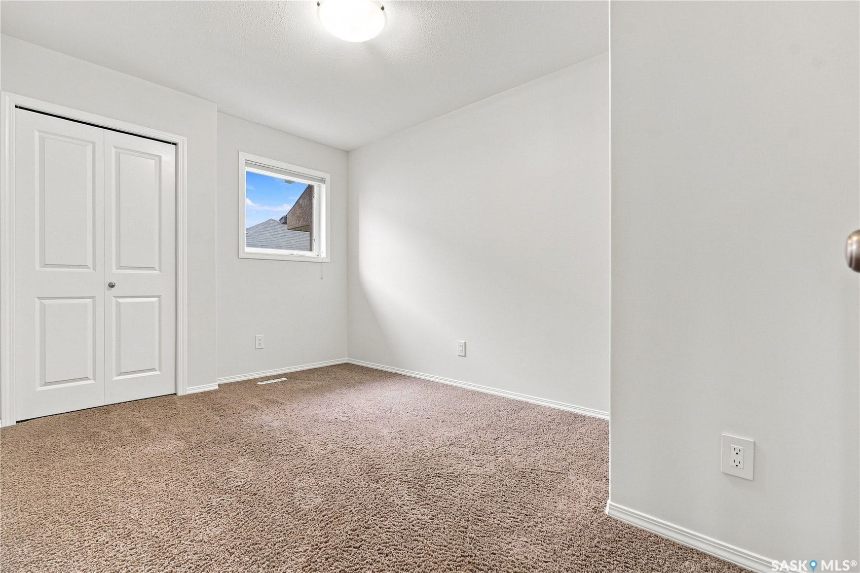Neutral wall color, window with natural light, textured carpeting, contemporary light fixture, and white bi-fold closet doors