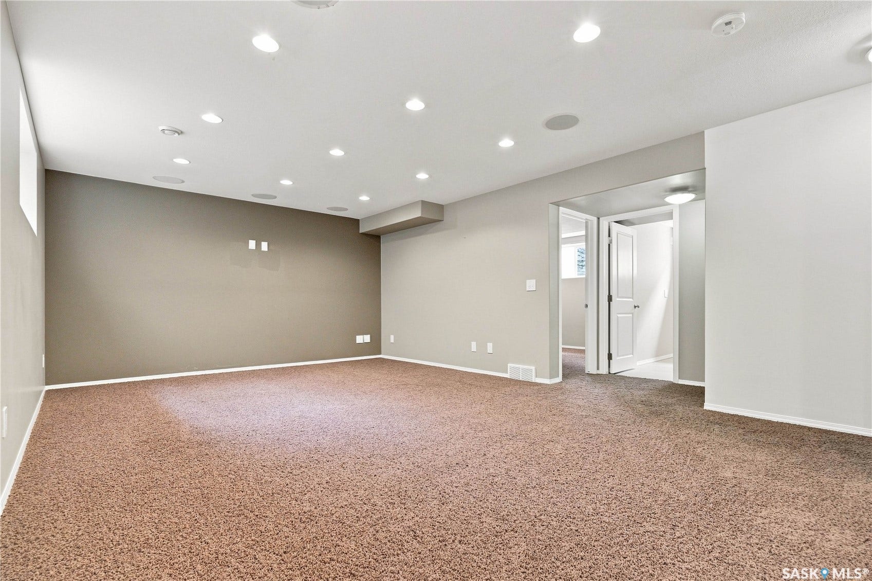 Recessed ceiling lighting, in-ceiling speakers, broadloom carpet, and neutral wall paint