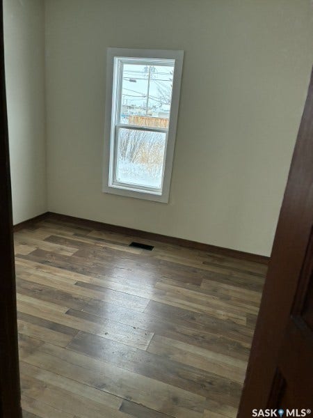 Wood-finish flooring with a neutral wall color and white trim around the window
