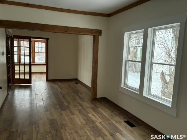 Wood-finish flooring throughout, featuring a broad entryway with wood beam accents