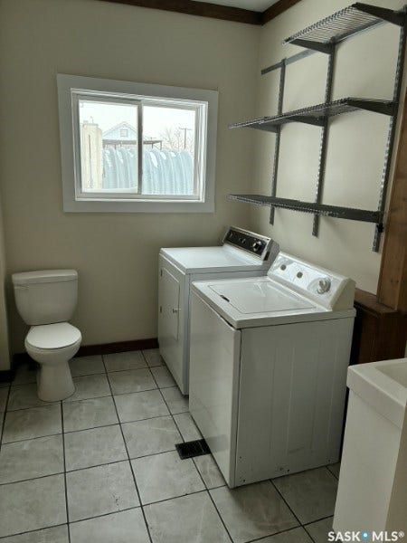 Tile flooring, window, wall-mounted shelving, built-in toilet, and an integrated sink with vanity cabinetry