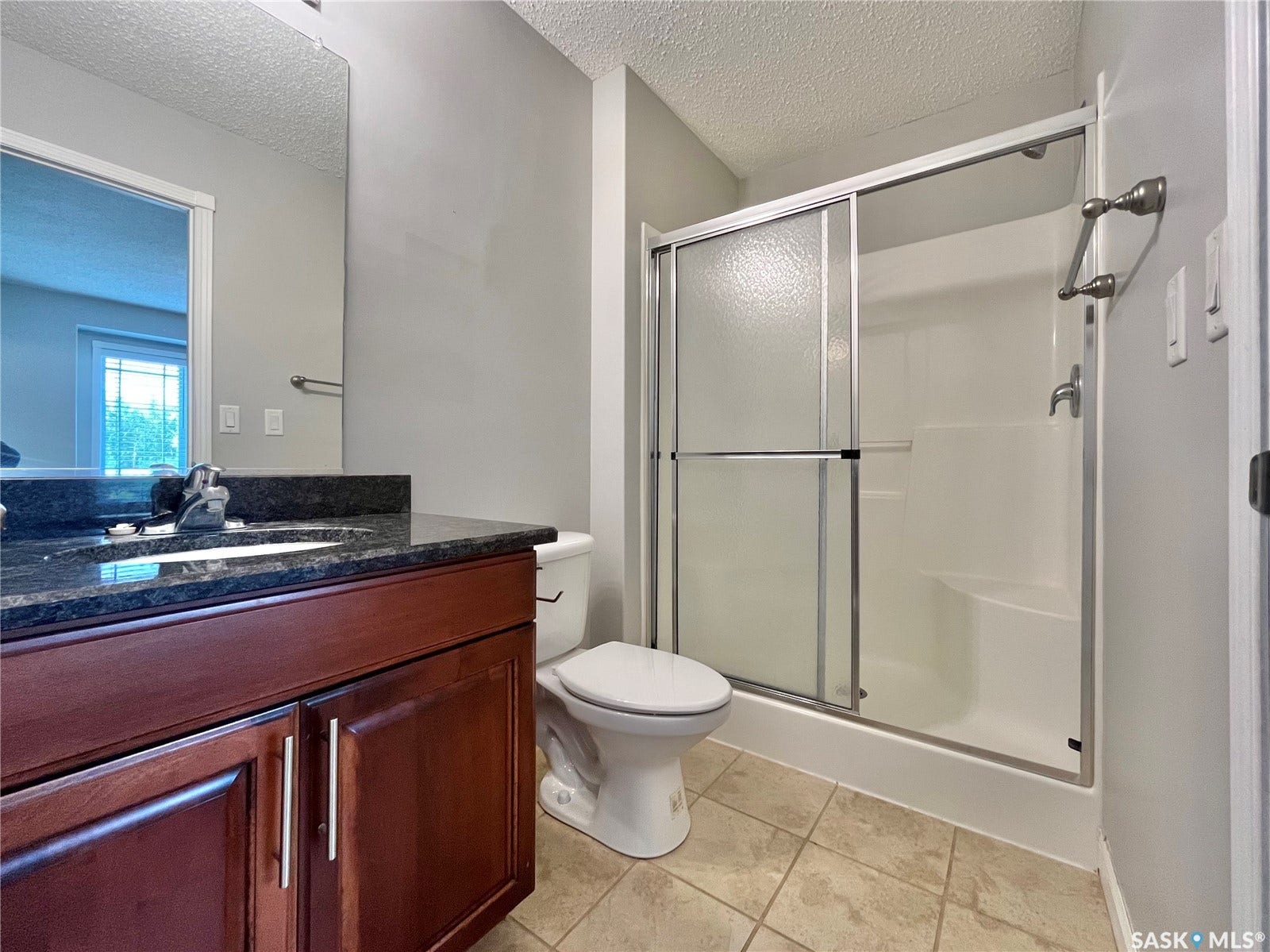 Dark-toned vanity with stone countertop, integrated sink, and brushed nickel faucet