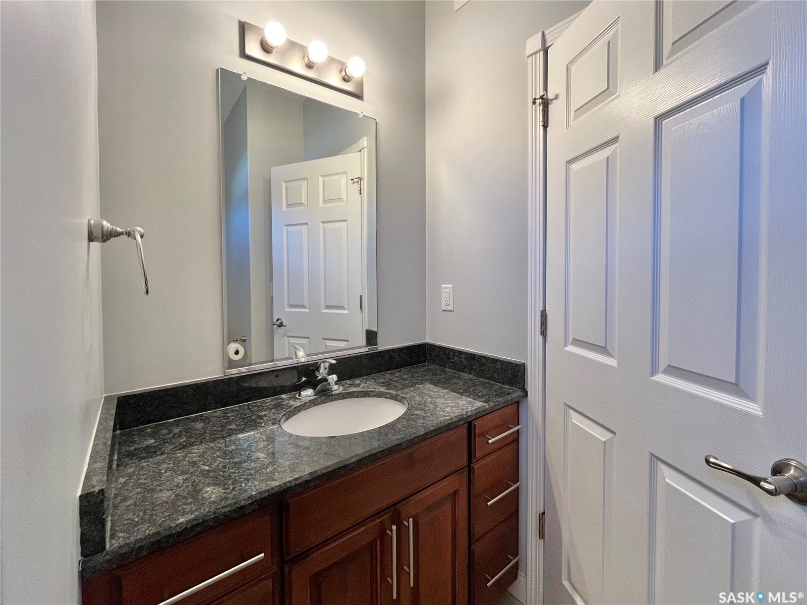 Vanity with granite countertop, integrated sink, and wood-finish cabinetry