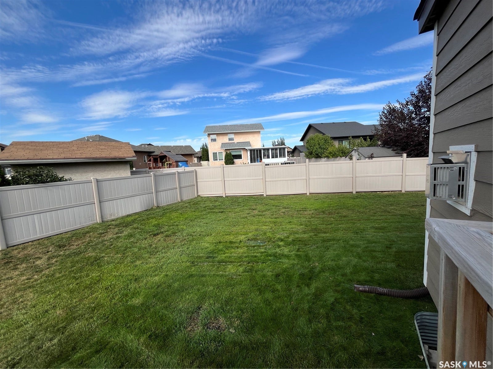 Expansive backyard with a manicured lawn, full perimeter fencing, and mature landscaping