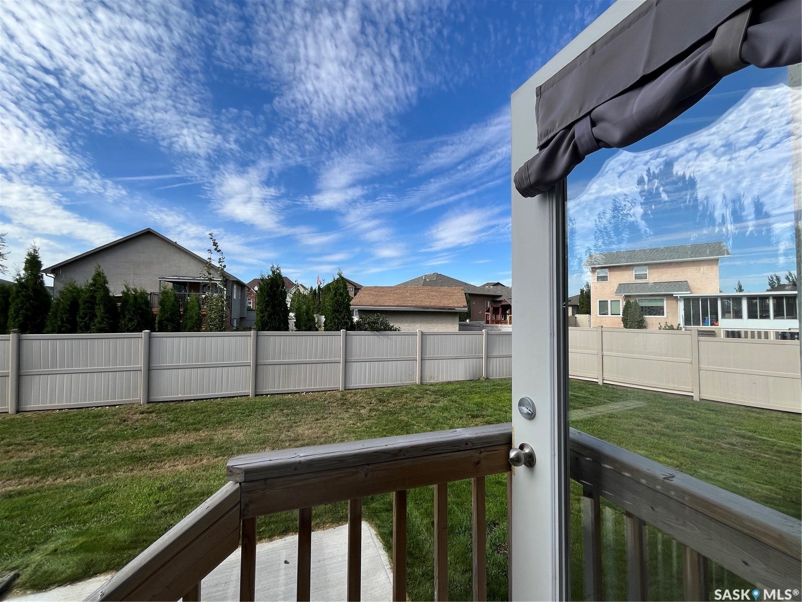 Private backyard with a vinyl fence, wood deck, and green lawn
