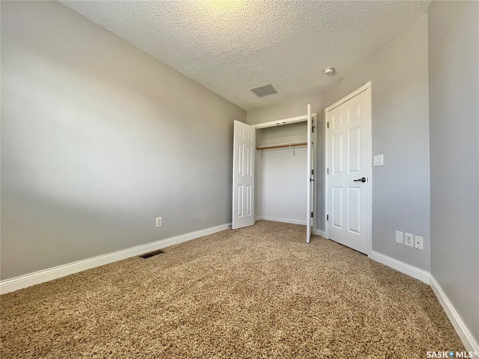 Wall-to-wall carpeting, painted walls, white trim, and a built-in closet with double doors and hanging storage