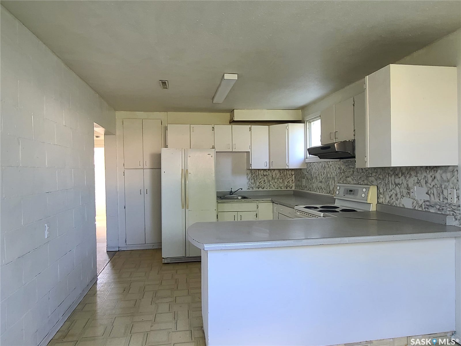 Kitchen featuring ample white cabinetry, a built-in range, a double basin sink, and a breakfast bar