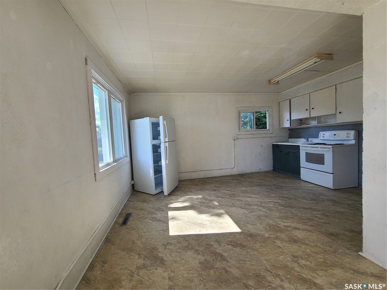 Kitchen space featuring a white electric range, upper cabinetry, lower cabinetry, and a utility sink